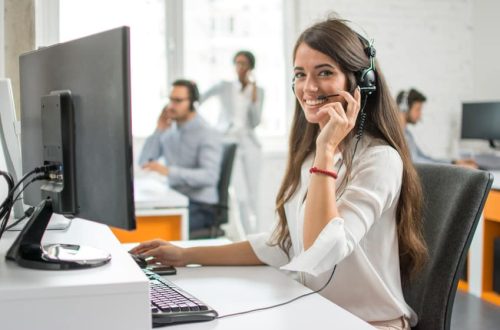 Young friendly operator woman agent with headsets working in a call centre.