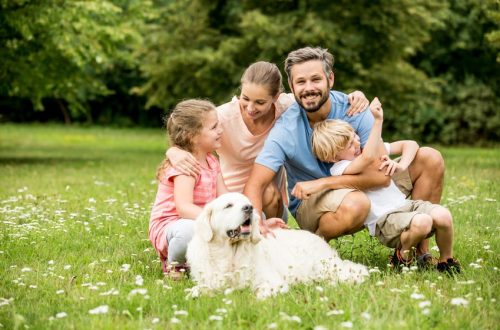 Glückliche Familie mit Kinder und Hund zusammen im Garten im Sommer
